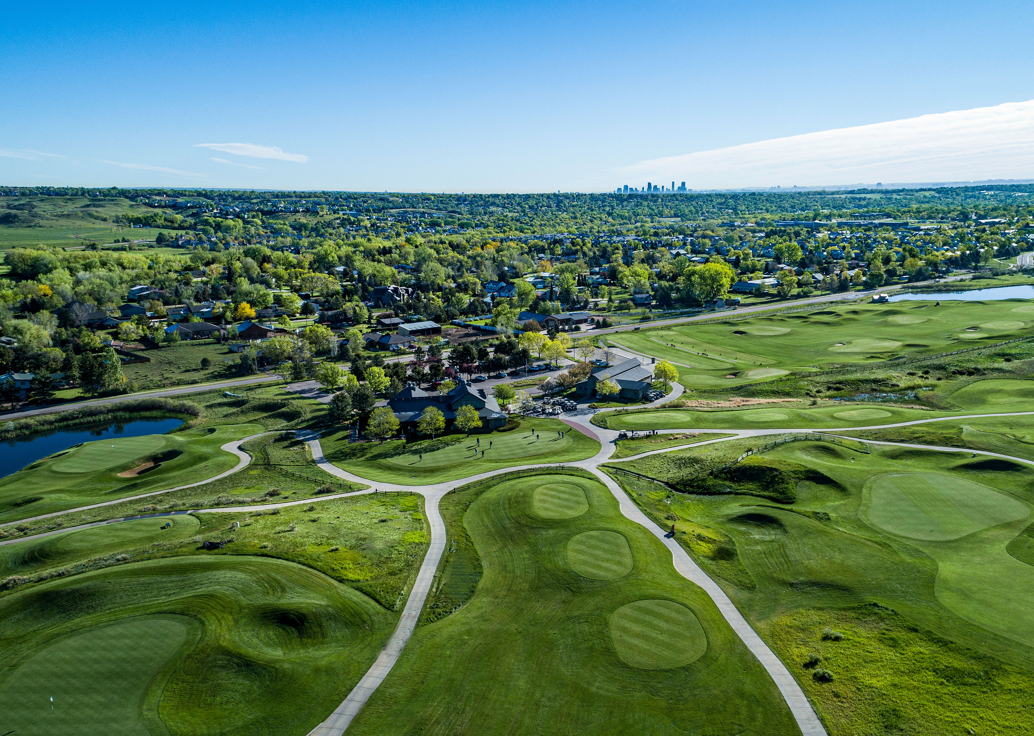 aerial view of Homestead's clubhouse and surrounding fairways, tee boxes and greens looking east with the Denver skyline in the background