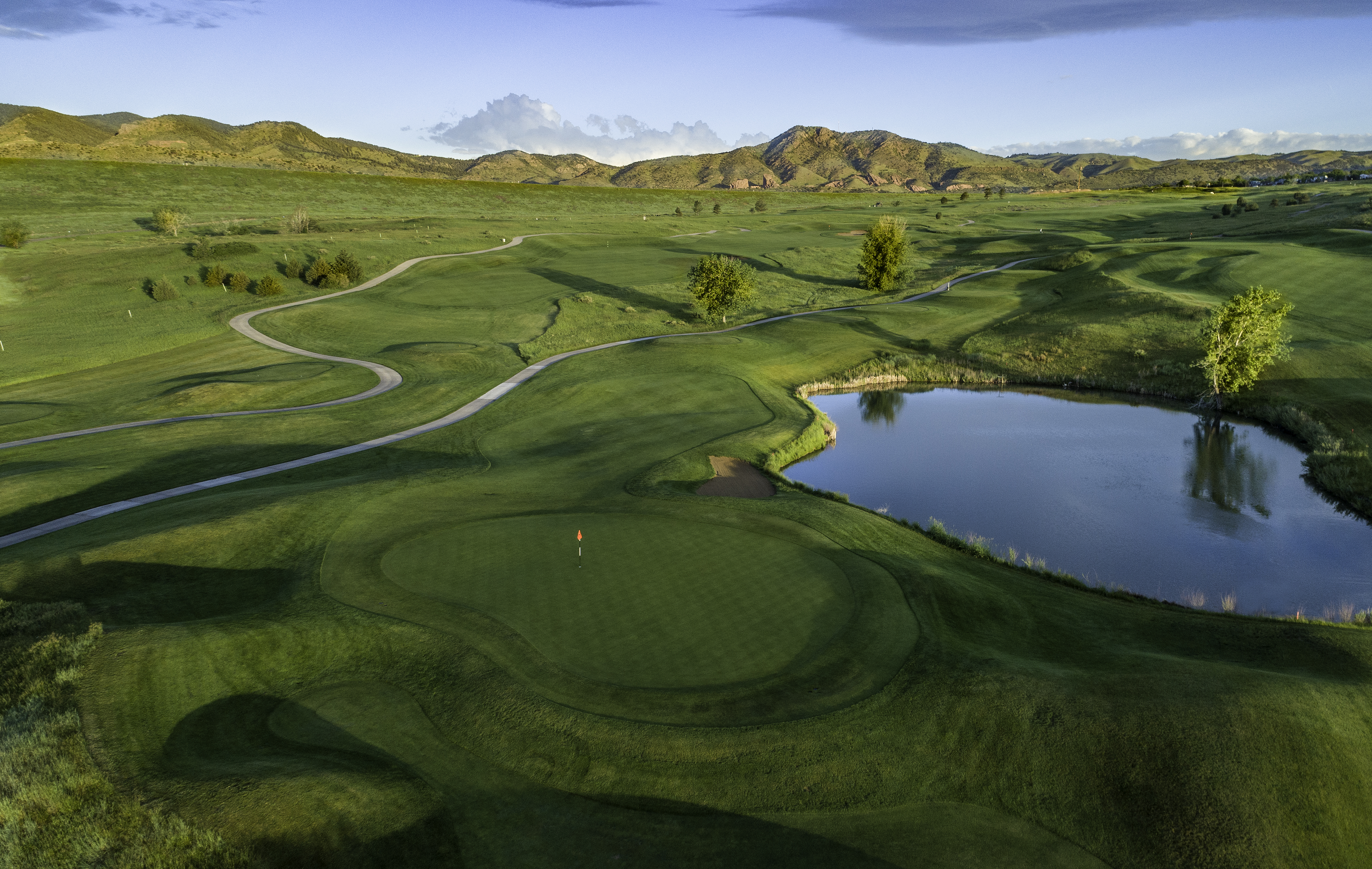 aerial view of Fox Hollow's Links #4 with water feature and Rocky Mountains in the background